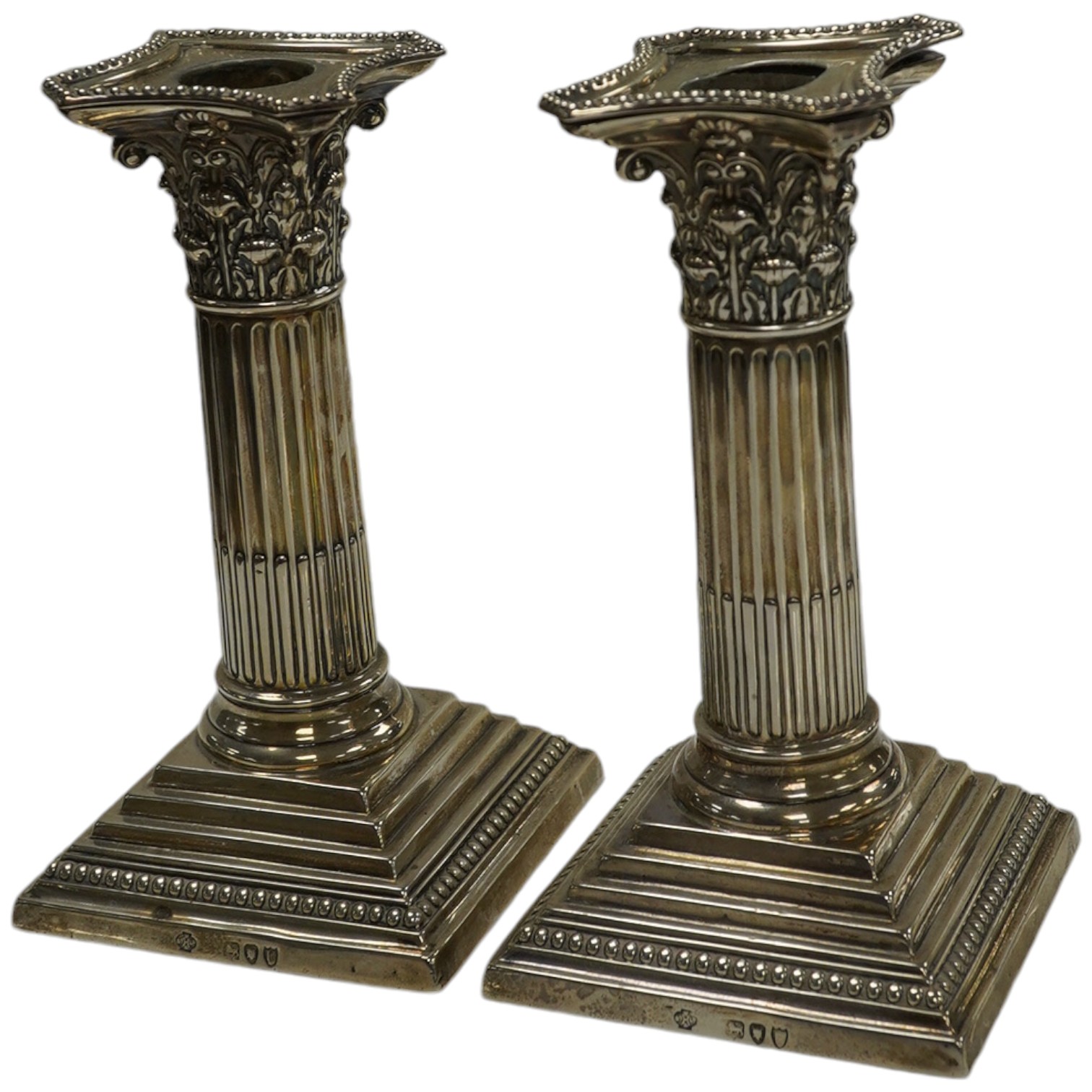 A pair of late Victorian silver Corinthian column dwarf candlesticks by William Comyns & Sons, London, 1895, 14.6cm, weighted. Condition - poor